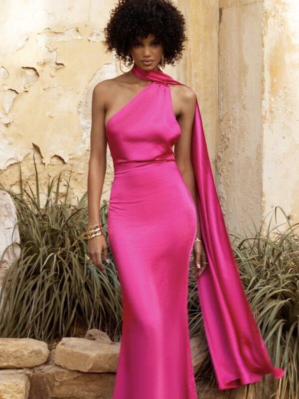 Lady with afro and chocolate brown skin in hot pink maxi dress staring straight ahead.